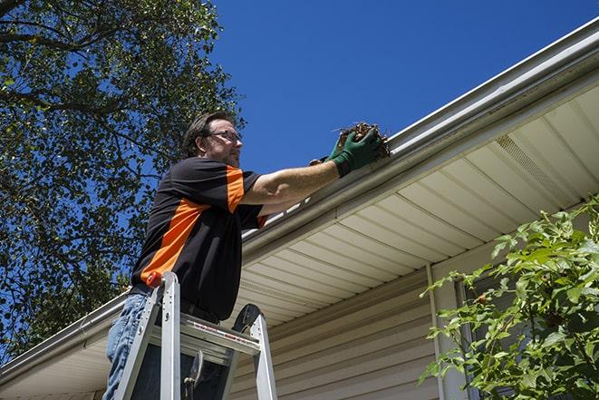 repairing a damaged rain gutter on a sunny day in Burlington NJ